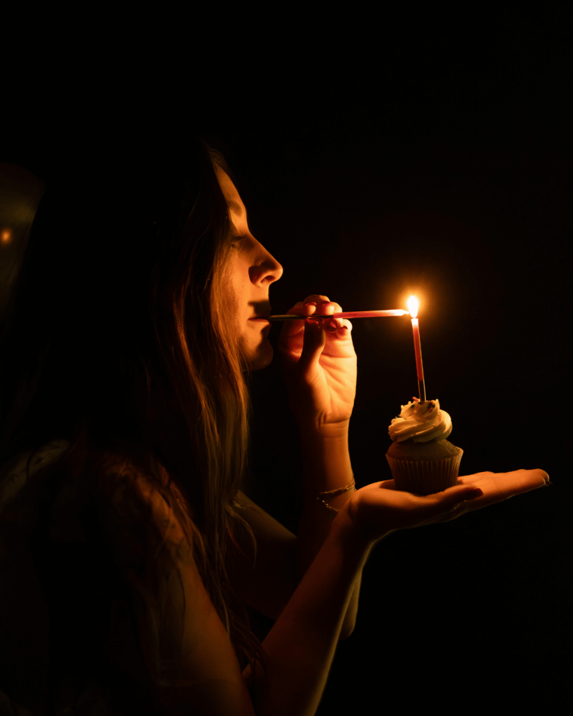 Woman lighting a birthday candle during a celebration boudoir photography session in Evansville, Indiana.