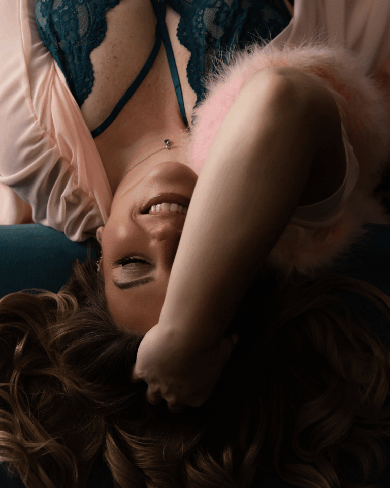 Smiling woman lying on a bed during a luxury boudoir photography session in Evansville, Indiana.
