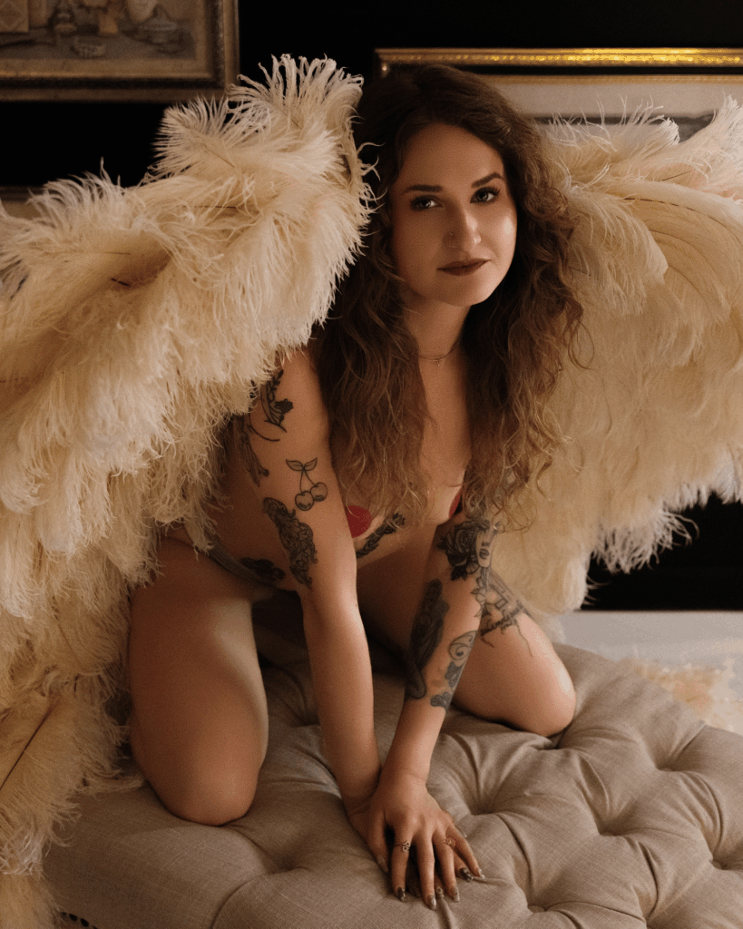 Woman posing with large angel wings during a themed boudoir photography session in Evansville, Indiana.